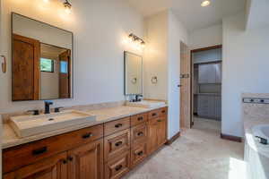 Bathroom featuring tiled bath, tile patterned flooring, and vanity