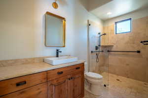 Bathroom with a tile shower, vanity, and toilet