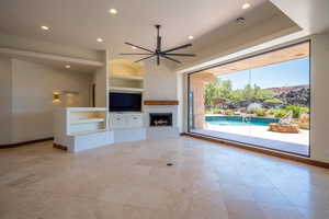 Unfurnished living room with ceiling fan and built in features