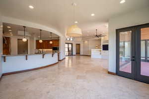 Kitchen featuring pendant lighting, french doors, ceiling fan, a kitchen bar, and kitchen peninsula