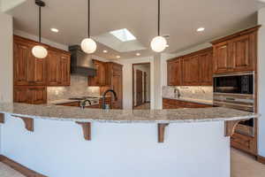 Kitchen featuring premium range hood, a skylight, oven, and hanging light fixtures