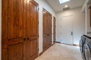 Washroom featuring cabinets, a skylight, and washer and clothes dryer