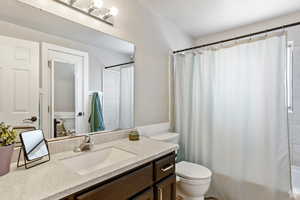 Full bathroom with shower / bath combo with shower curtain, vanity, and toilet