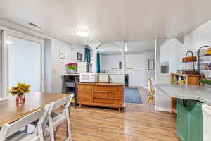 Kitchen featuring white appliances, a textured ceiling, light hardwood / wood-style flooring, and green cabinetry