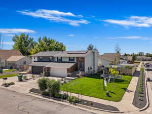 View of front of property featuring a trampoline, a garage, a front yard, and solar panels