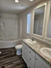 Full bathroom featuring hardwood / wood-style floors, vanity, toilet, and shower / bath combination