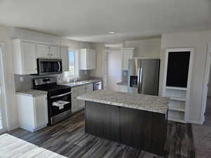 Kitchen featuring a center island, white cabinets, and stainless steel appliances