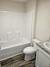 Full bathroom featuring vanity, wood-type flooring, shower / bathtub combination, and toilet