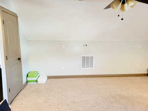 Empty room with light colored carpet, vaulted ceiling, and ceiling fan