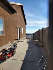 View of side of home with a water view and a patio