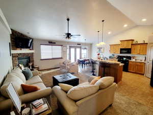 Living room featuring vaulted ceiling, a stone fireplace, ceiling fan, and sink
