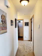 Hallway with carpet floors and an AC wall unit