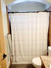 Bathroom with curtained shower, vanity, and toilet