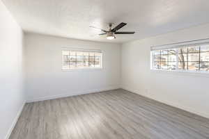 Empty room featuring a textured ceiling, light hardwood / wood-style flooring, and ceiling fan