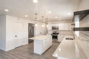 Kitchen featuring white cabinets, a kitchen island, sink, and stainless steel appliances