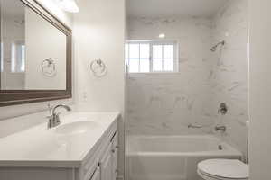 Full bathroom featuring vanity, tiled shower / bath combo, and toilet