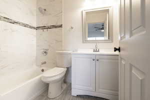 Full bathroom featuring vanity, tiled shower / bath combo, and toilet