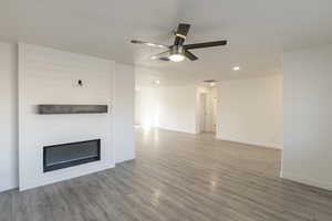 Unfurnished living room featuring a textured ceiling, light wood-type flooring, and ceiling fan