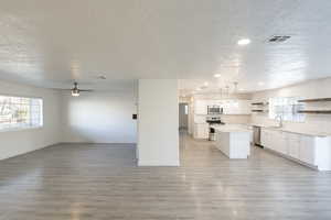 Kitchen with white cabinets, sink, appliances with stainless steel finishes, decorative light fixtures, and a kitchen island