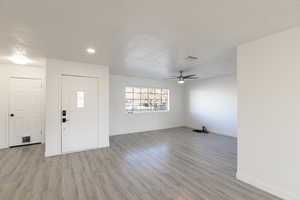 Entrance foyer featuring a textured ceiling, light wood-type flooring, and ceiling fan