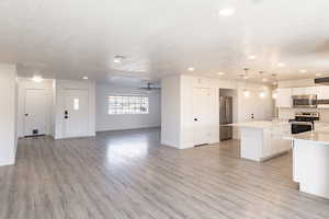 Kitchen with stainless steel appliances, ceiling fan, decorative light fixtures, white cabinets, and a center island