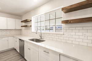 Kitchen with dishwasher, backsplash, white cabinets, sink, and light hardwood / wood-style flooring