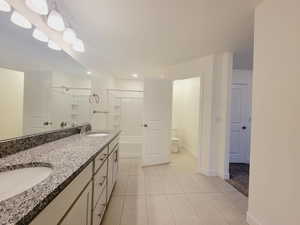 Attached bathroom for Main bedroom suite. 2 sinks, tile flooring, tub/shower combination unit, and separated toilet room