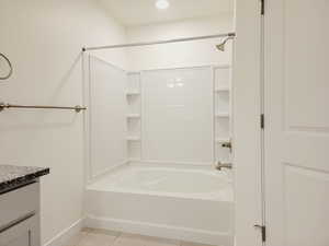 Attached bathroom for Main bedroom suite. 2 sinks, tile flooring, tub/shower combination unit, and separated toilet room