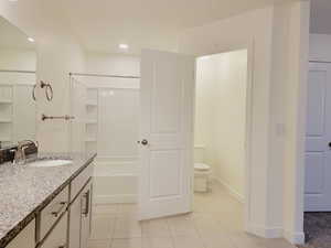 Attached bathroom for Main bedroom suite. 2 sinks, tile flooring, tub/shower combination unit, and separated toilet room