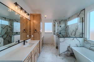 Bathroom featuring independent shower and bath, vanity, and a healthy amount of sunlight