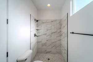 Bathroom featuring a tile shower and toilet