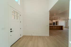 Entryway featuring a towering ceiling, light hardwood / wood-style floors, and an inviting chandelier