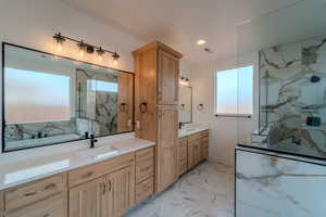 Bathroom featuring tiled shower, vanity, and plenty of natural light