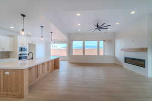 Kitchen featuring ceiling fan, pendant lighting, a spacious island, white cabinets, and appliances with stainless steel finishes