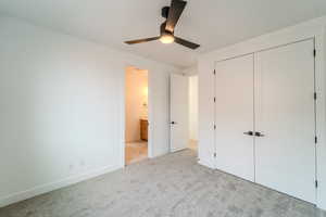 Unfurnished bedroom featuring ceiling fan, a closet, ensuite bathroom, and light colored carpet