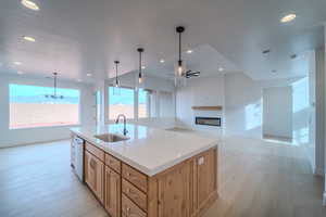 Kitchen with ceiling fan with notable chandelier, a kitchen island with sink, sink, decorative light fixtures, and dishwasher