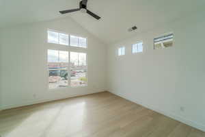 Empty room with ceiling fan, a healthy amount of sunlight, a high ceiling, and light hardwood / wood-style floors