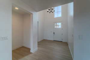 Foyer entrance featuring light wood-type flooring, a high ceiling, and an inviting chandelier