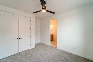 Unfurnished bedroom with ceiling fan, ensuite bathroom, light carpet, and a closet