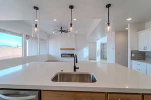 Kitchen featuring white cabinets, light stone countertops, sink, and a kitchen island with sink