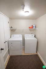 Laundry area with washing machine and clothes dryer, light tile patterned floors, and a textured ceiling