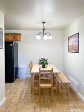 Dining space with a notable chandelier, light tile patterned floors, and a textured ceiling