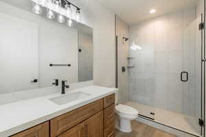 Bathroom with vanity, wood-type flooring, an enclosed shower, and toilet