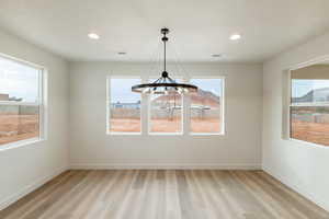 Unfurnished dining area featuring a chandelier, a healthy amount of sunlight, and light wood-type flooring