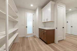 Bar featuring white cabinetry and light wood-type flooring