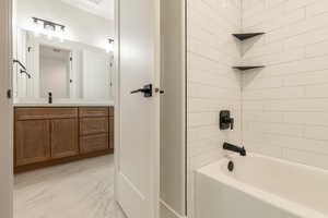 Bathroom featuring vanity and tiled shower / bath