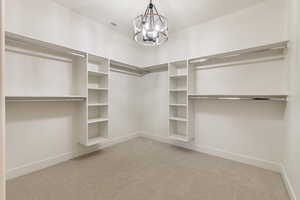 Spacious closet featuring light carpet and a chandelier