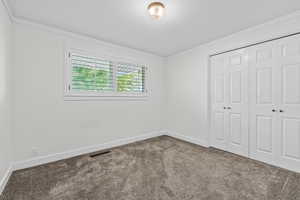 Unfurnished bedroom featuring a closet, carpet floors, and ornamental molding