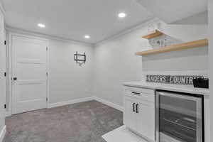 Bar featuring white cabinets, light colored carpet, and beverage cooler