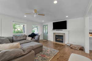 Living room with hardwood / wood-style floors, ceiling fan, ornamental molding, and a fireplace